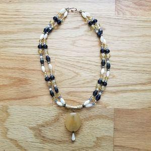 Beaded double strand necklace with large stone pendant.